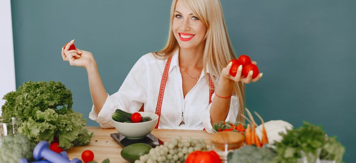 Healthy lifestyle concept with woman holding tomatoes and surrounded by fresh vegetables in a studio setting.